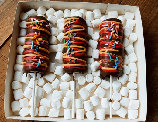 Arreglo frutal Caj-78 Brochetas de bombones con chocolate sobre una cama de mini bombones devorame